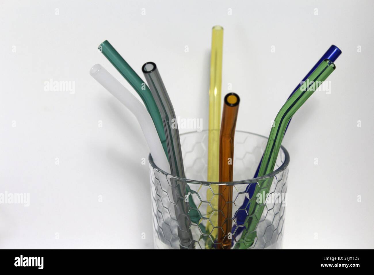 Colorful reusable glass straws in a clear glass cup. An alternative replacement for classic disposable plastic drinking straw great for the environment Stock Photo