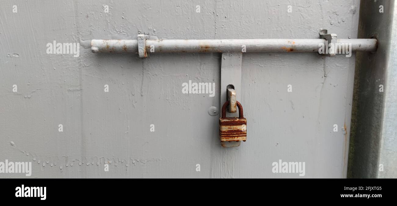 The lock on a chain hangs on a gate with white plate Stock Photo