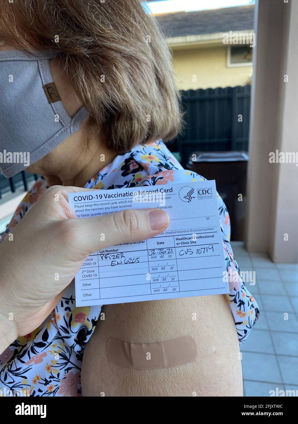 Closeup of COVID-19 vaccination record card by the CDC. Masked senior woman after receiving covid-19 vaccine at her local pharmacy showing from CVS Stock Photo