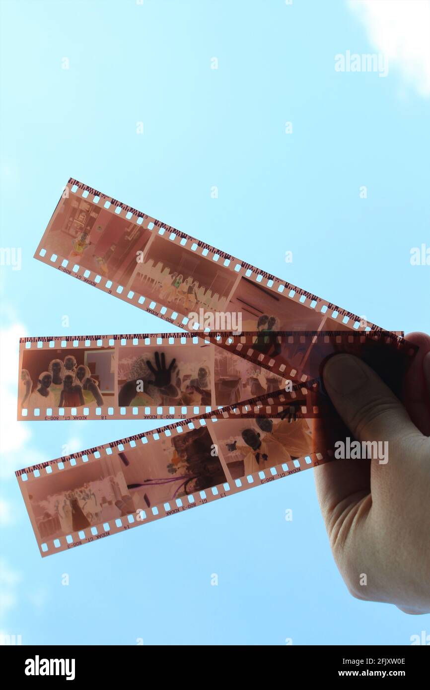 Hand holding old Kodak vintage film negative photography, retro image frame on filmstrip in the air behind the clouds in the sky with copy space Stock Photo