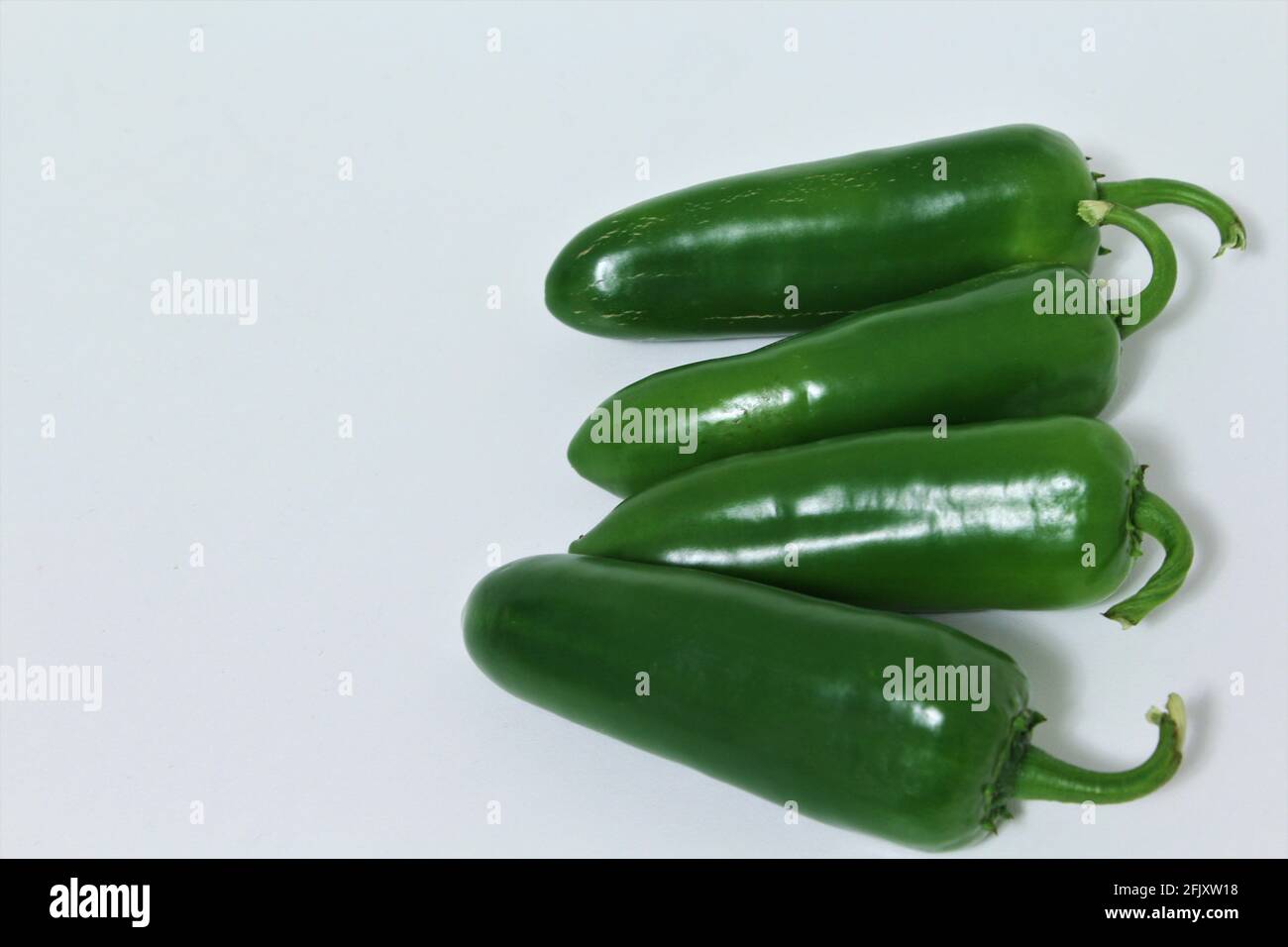 Green Jalapeno Chile peppers grouped together on a white background