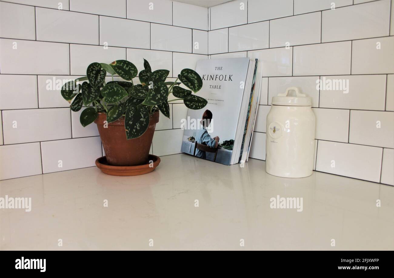 Kitchen counter showing kitchen cookbooks such as the famous The Kinfolk Table magazine alongside a honey jar and small house plant. Minimalistic Stock Photo