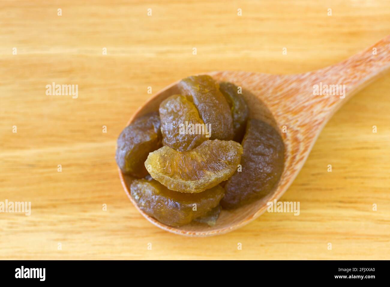 Dried Amla Indian gooseberry fruit in wood spoon on wooden background (Phyllanthus emblica) Stock Photo