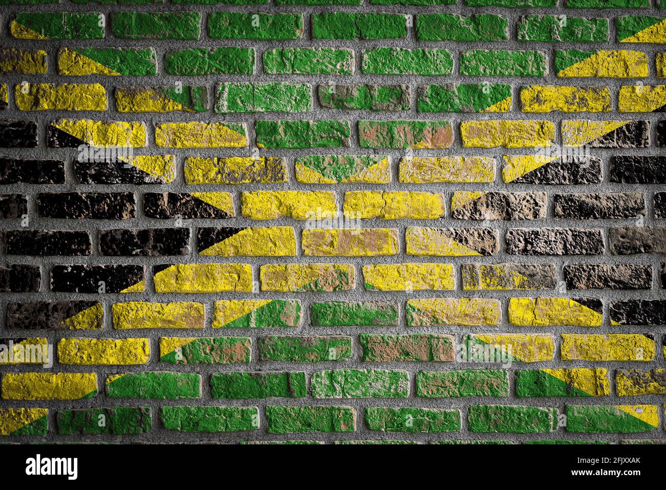 National flag of Jamaica depicting in paint colors on an old brick wall. Flag  banner on brick wall background. Stock Photo