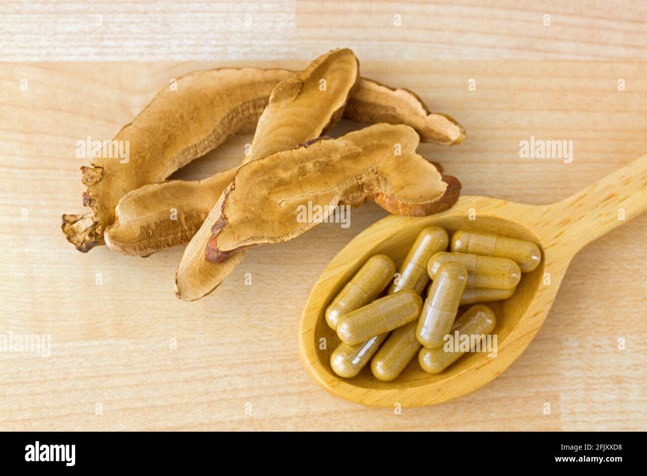 Herbal Lingzhi medicine in capsule next to sliced dried Reishi. It is medicinal mushroom in traditional Chinese medicine Stock Photo