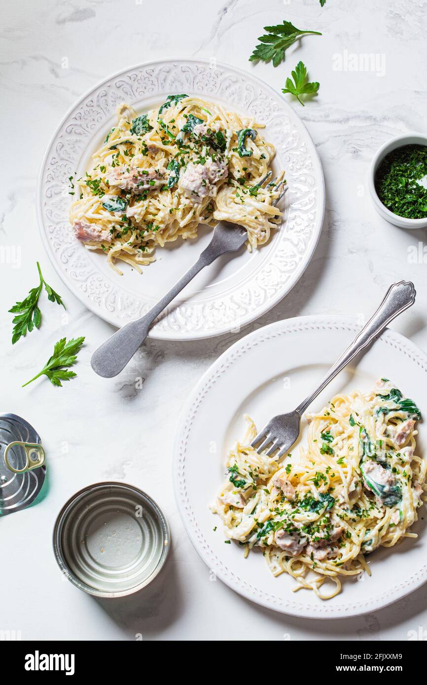 Spaghetti pasta with canned tuna, spinach and cream sauce on a white