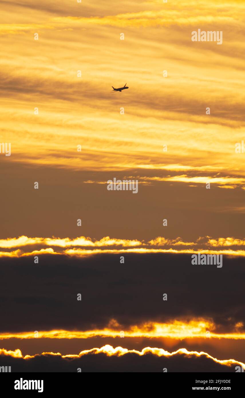 Wimbledon, London, UK. 27 April 2021. An early arrival to London Heathrow airport begins the descent against a colourful backdrop of early clouds at sunrise. Credit: Malcolm Park/Alamy Live News. Stock Photo