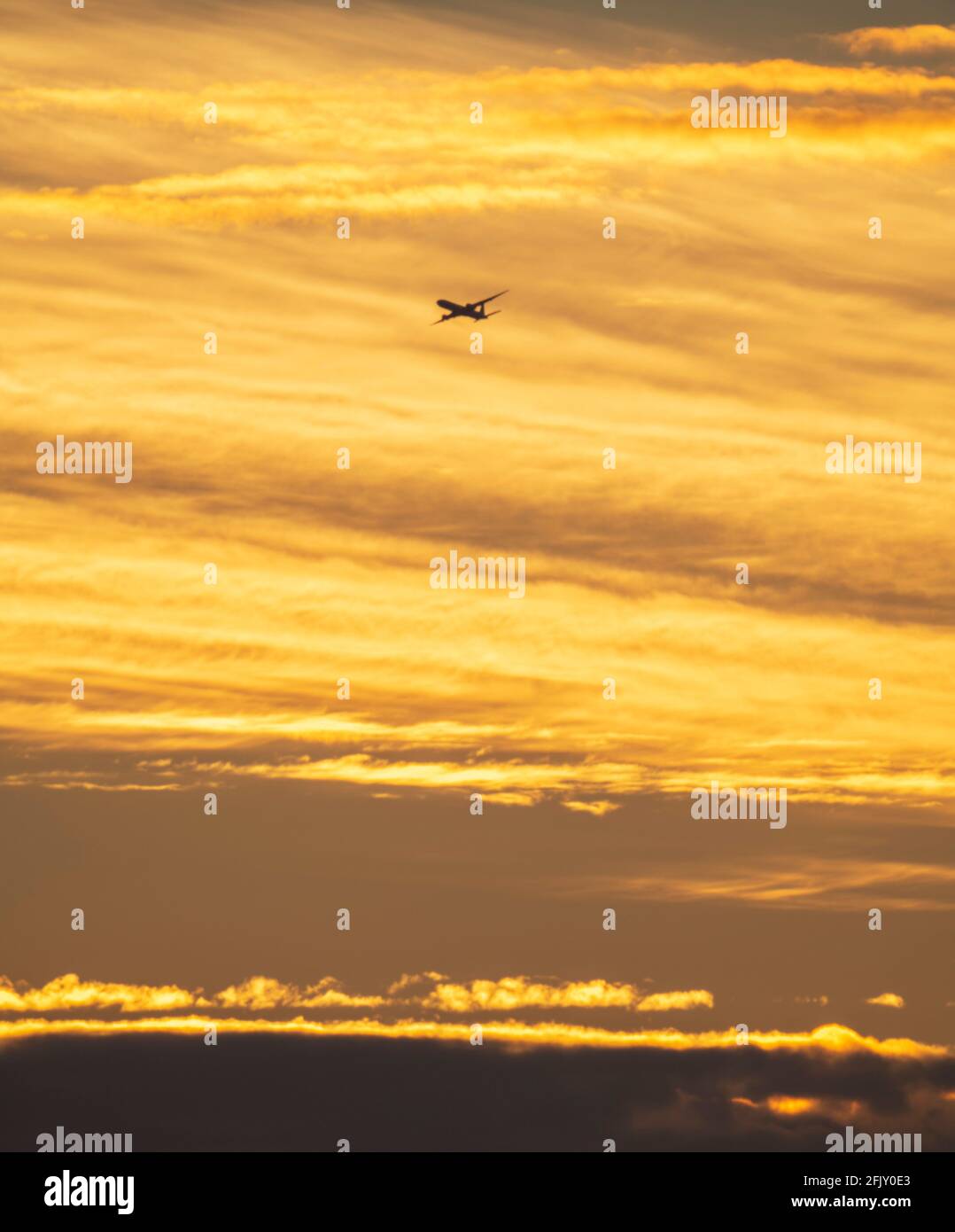 Wimbledon, London, UK. 27 April 2021. An early arrival to London Heathrow airport begins the descent against a colourful backdrop of early clouds at sunrise. Credit: Malcolm Park/Alamy Live News. Stock Photo