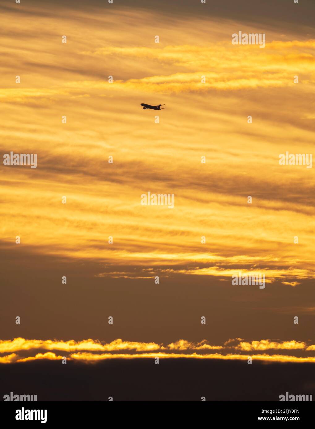 Wimbledon, London, UK. 27 April 2021. An early arrival to London Heathrow airport begins the descent against a colourful backdrop of early clouds at sunrise. Credit: Malcolm Park/Alamy Live News. Stock Photo