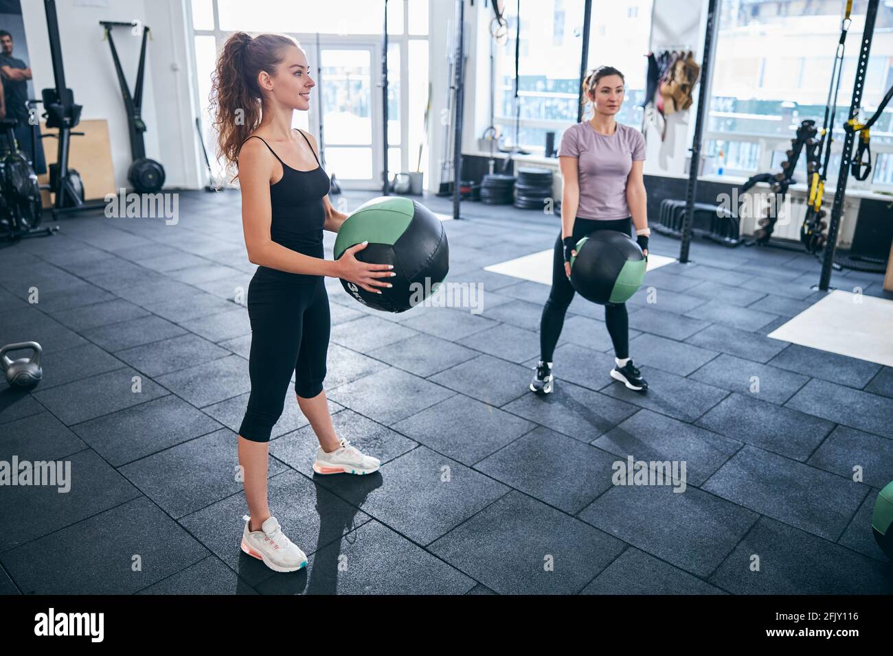 Two female athletes performing squats with exercise balls Stock Photo
