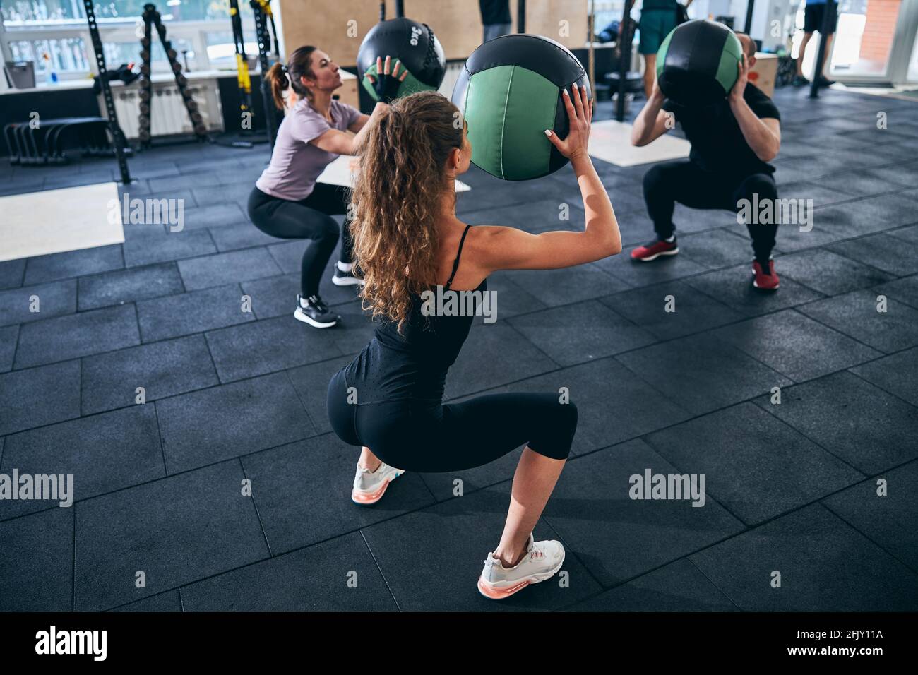 Three people doing squats with stability balls Stock Photo