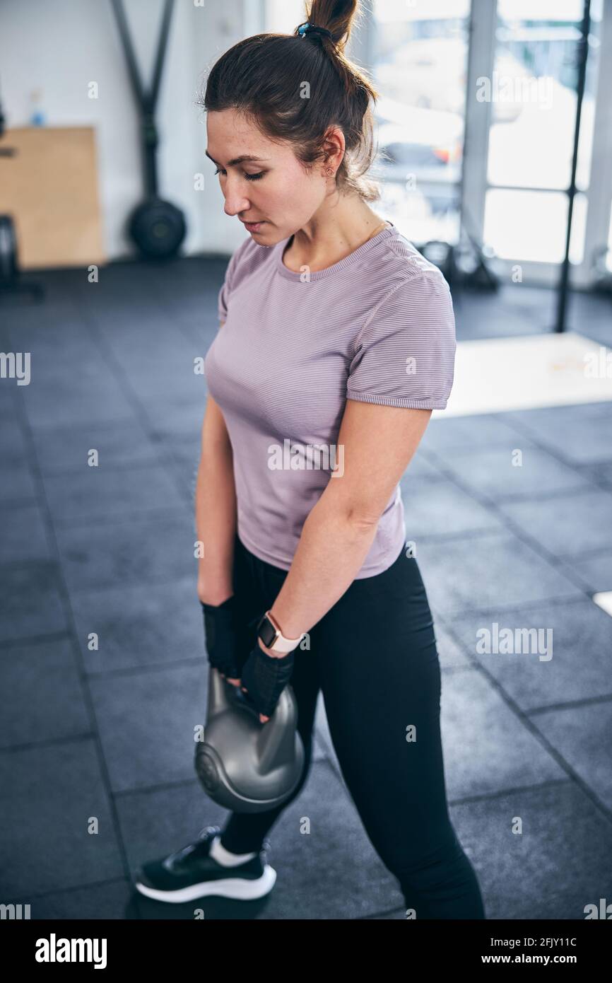 Serious dark-haired sportswoman doing a strength exercise Stock Photo