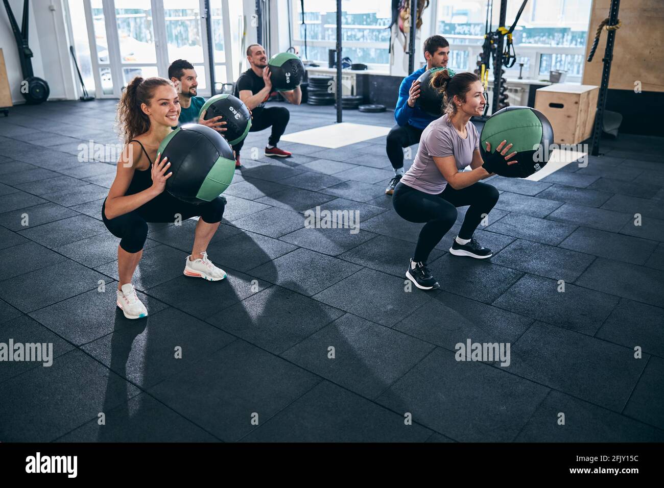 Five athletes exercising with stability balls indoors Stock Photo