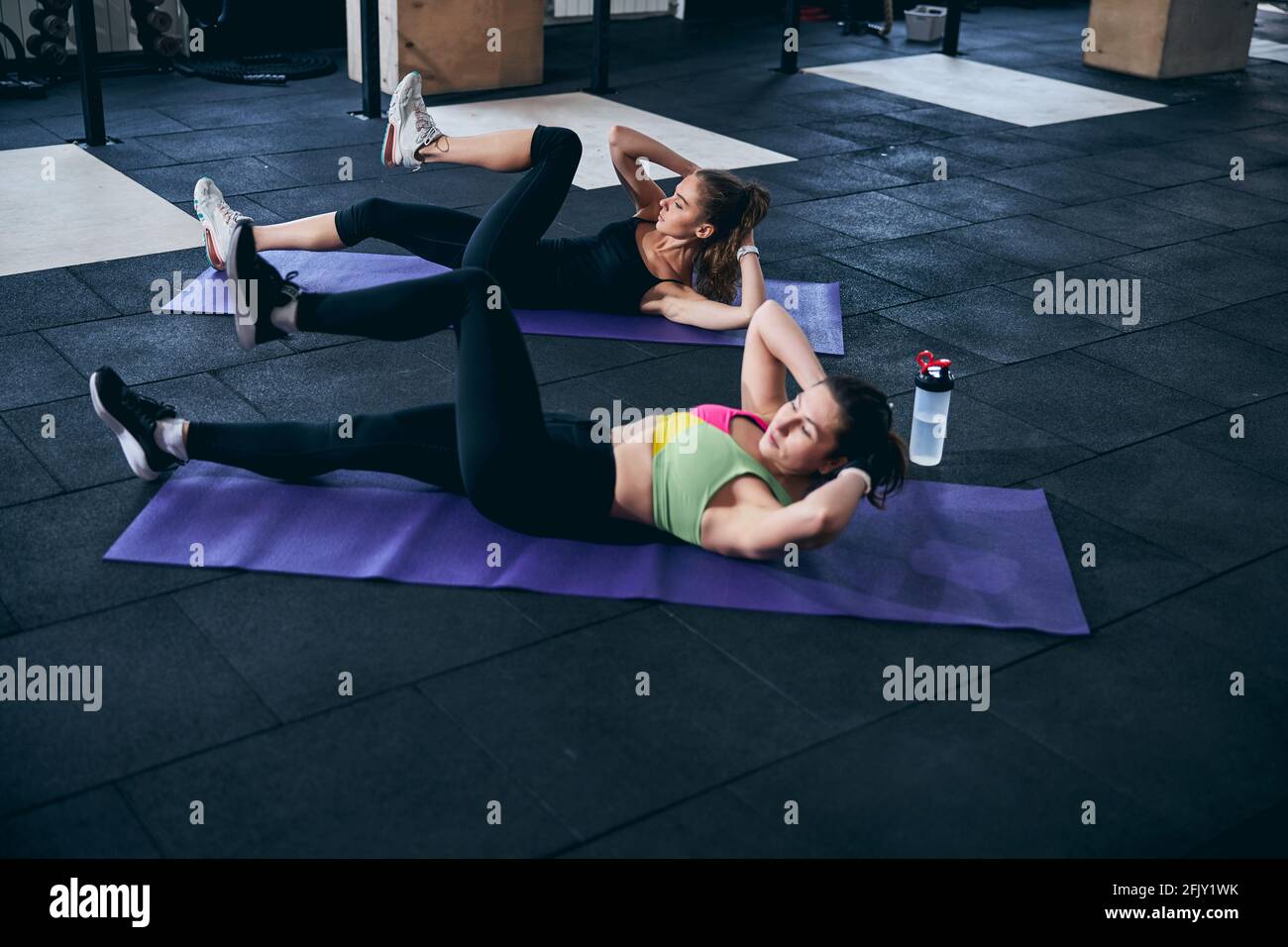 Fitness trainer and her client strengthening their upper abdominal muscles Stock Photo