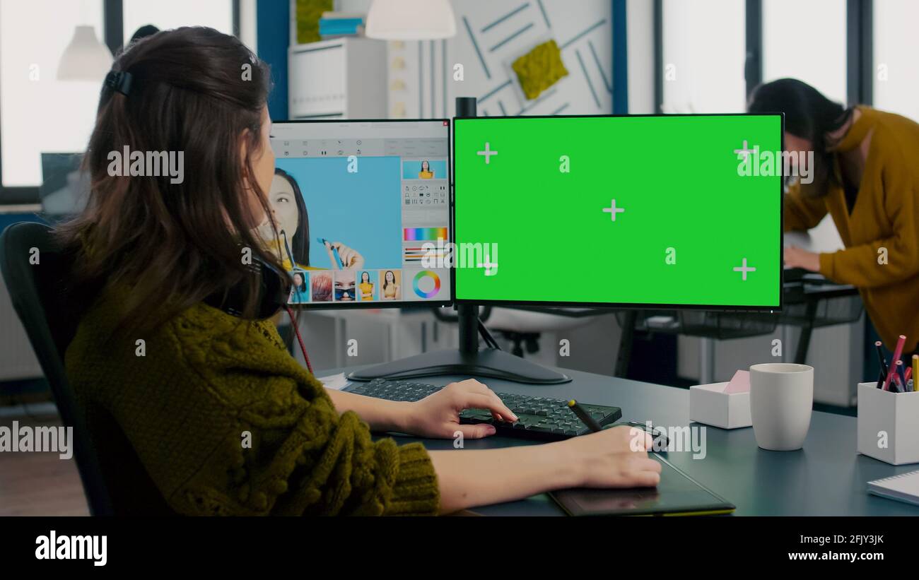 Photographer working on green mock-up screen, computer with chroma key ...