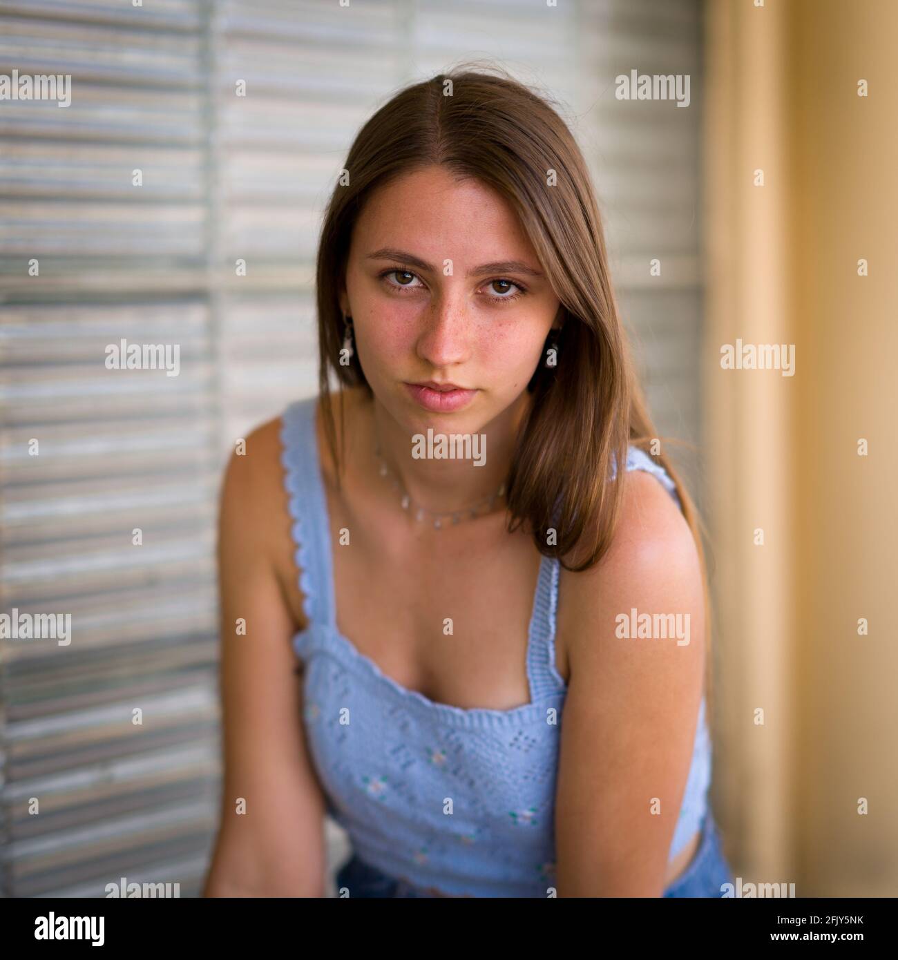 Portrait of young woman seated in front of an art deco glass wall Stock Photo