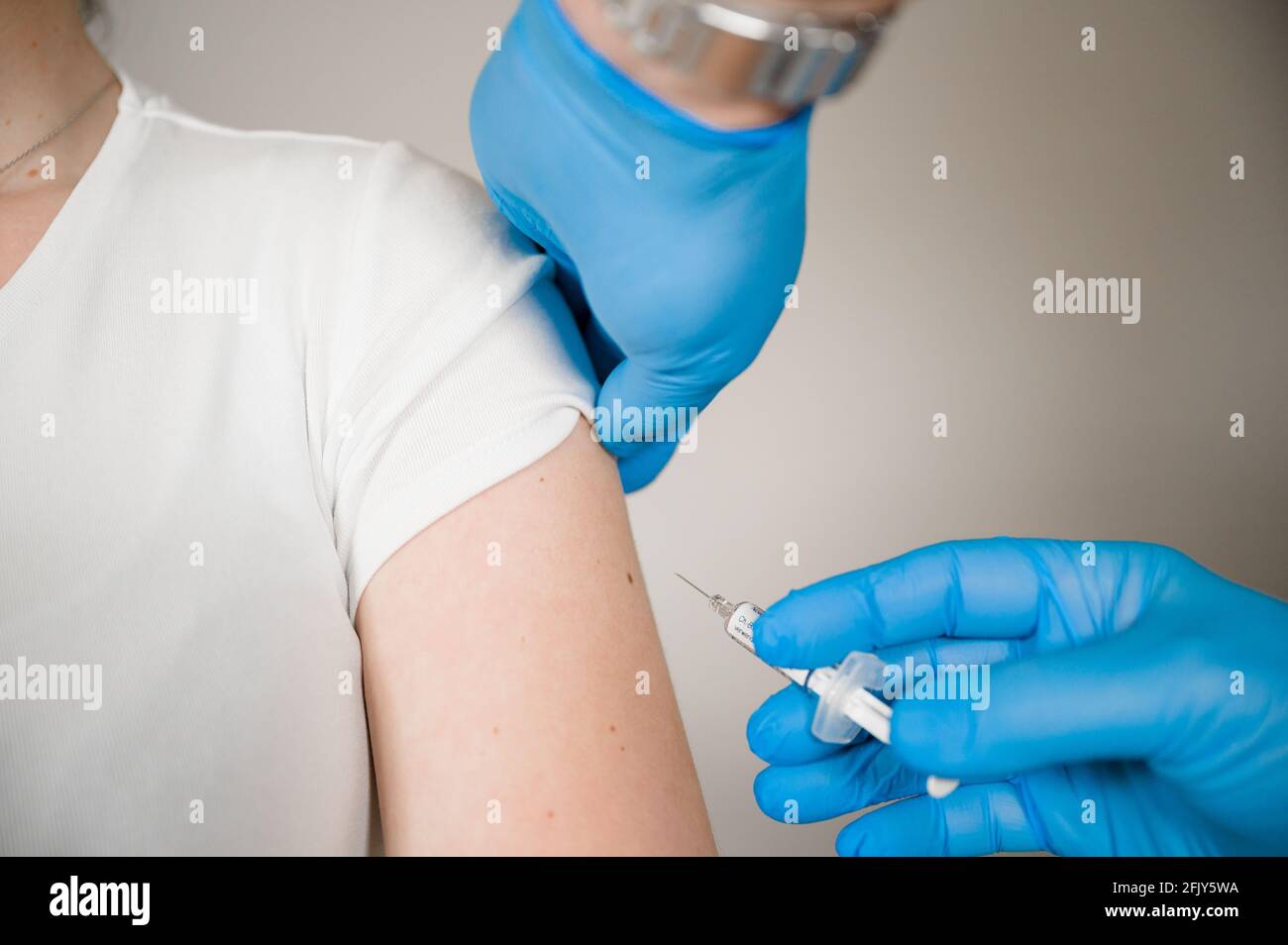 Doctor injecting Covid Vaccine into a patients arm: Curing the Corona Pandemic with mass Vaccination Stock Photo