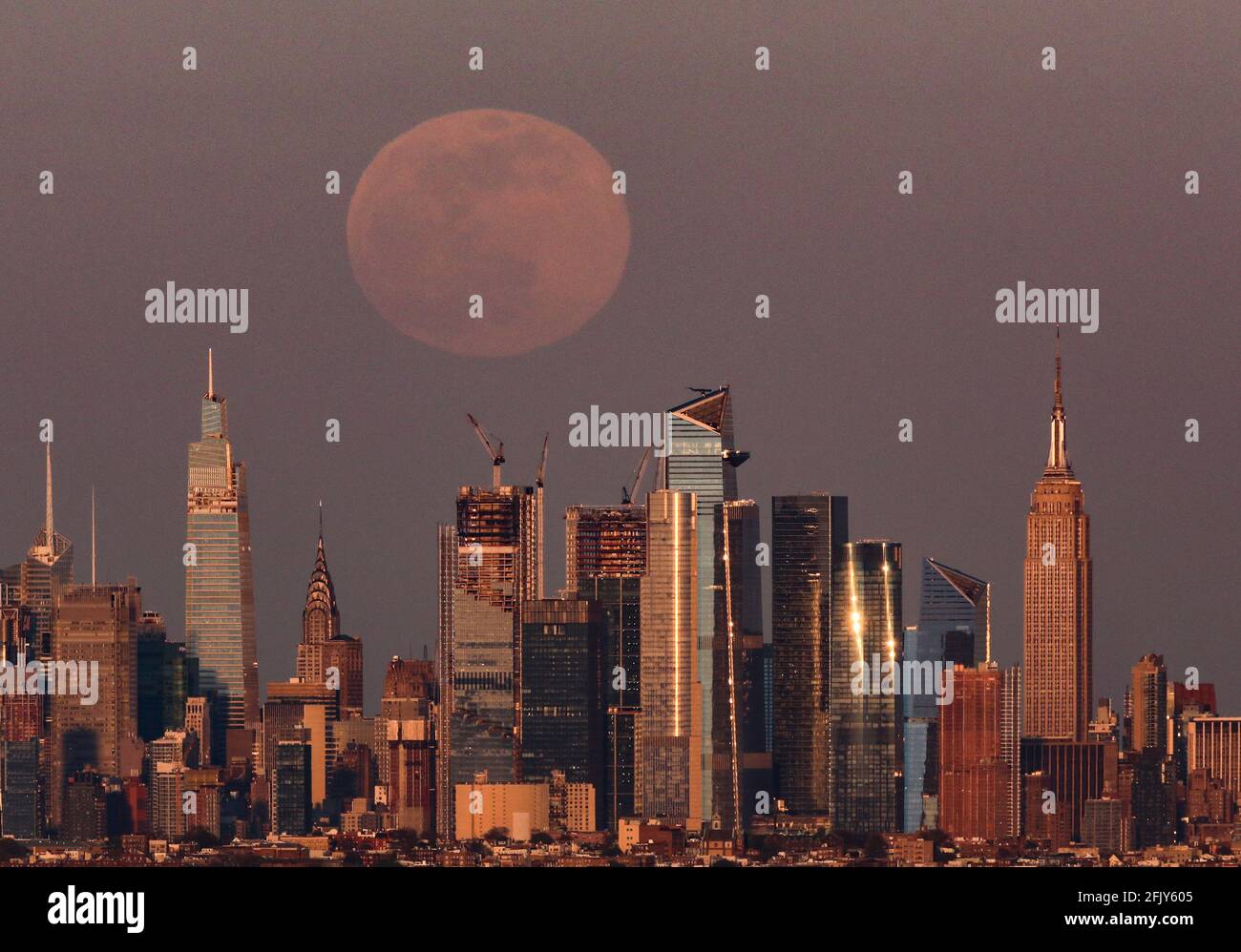 New York, USA. 26th Apr, 2021. Photo taken in West Orange of New Jersey on April 26, 2021 shows a super moon rising over the Manhattan skyline in New York, the United States. Credit: Wang Ying/Xinhua/Alamy Live News Stock Photo