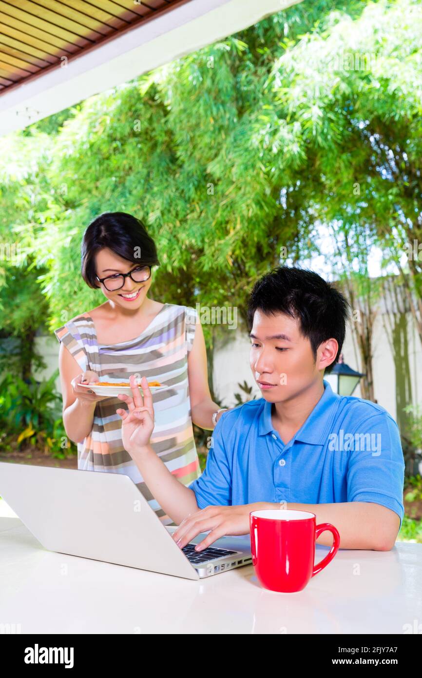 Chinese mother brings her son some food, he makes homework for the next day at school and is concentrated Stock Photo
