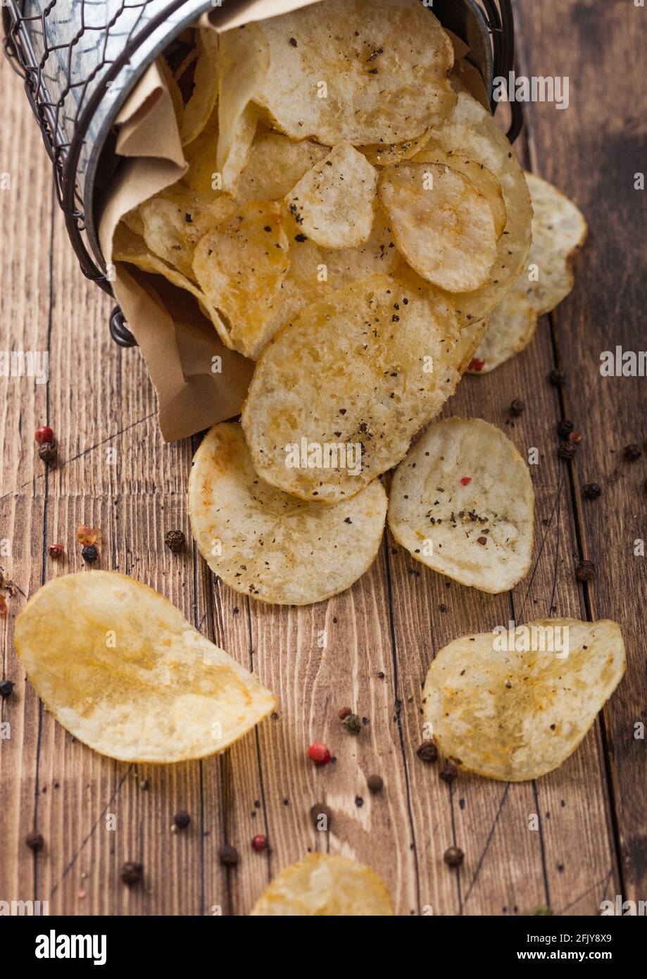 Black pepper taste potato crisps chips in steel snack bucket on wooden