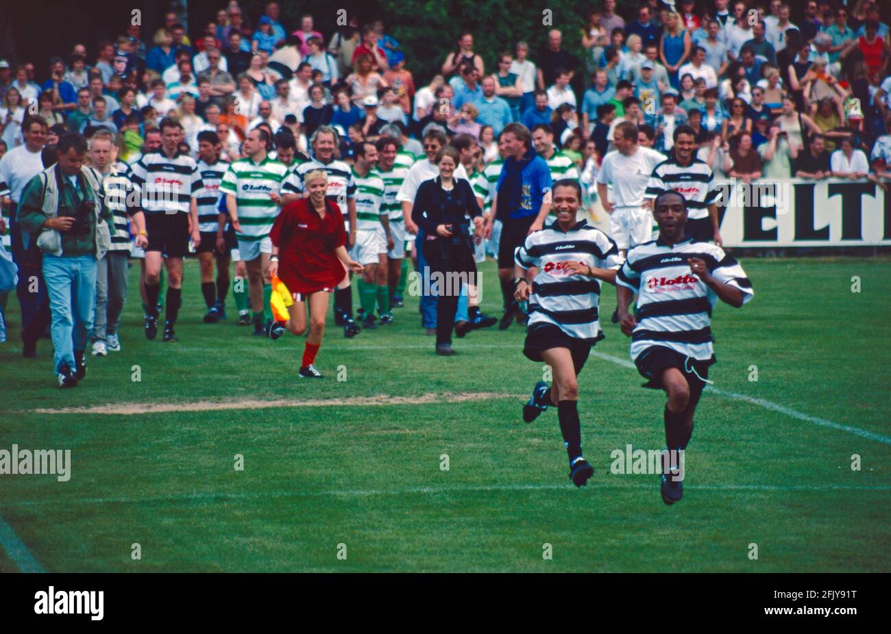 players running onto the field, in the background singer T. of Mr. President, in the front singer Lee of Tic Tac Toe and singer Lazy of Mr. President, on the occasion of a benefit match organised by the sports club LSK, May 17, 1998, Lüneburg, Lower Saxony, Germany Stock Photo