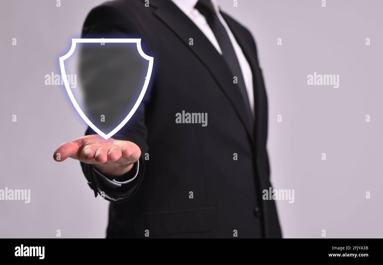 Man in a business suit shows a shield, the concept of protection and guarding Stock Photo