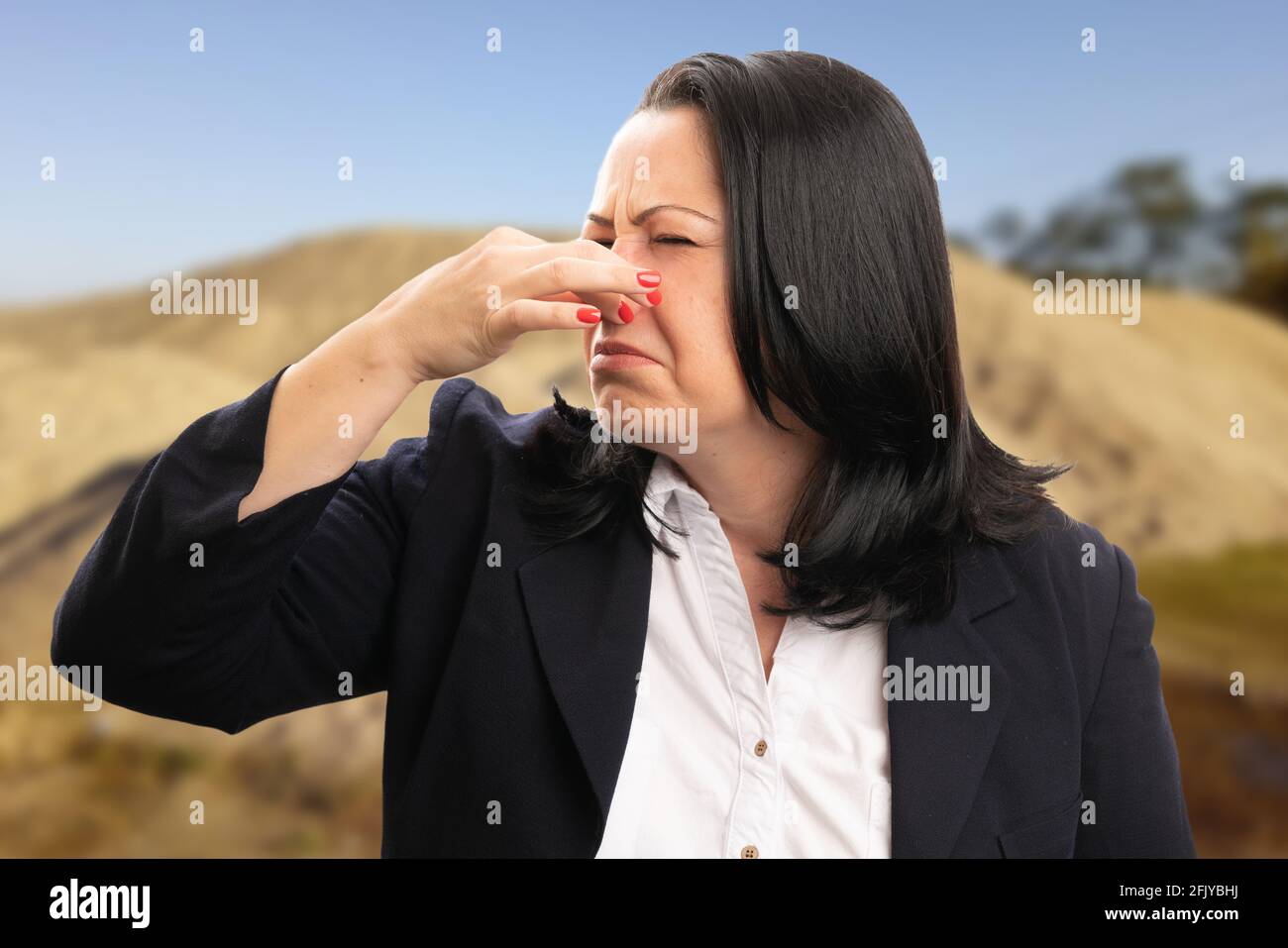 Female entrepreneur businesswoman wearing suit at construction site making bad smell gesture holding nose gross expression Stock Photo