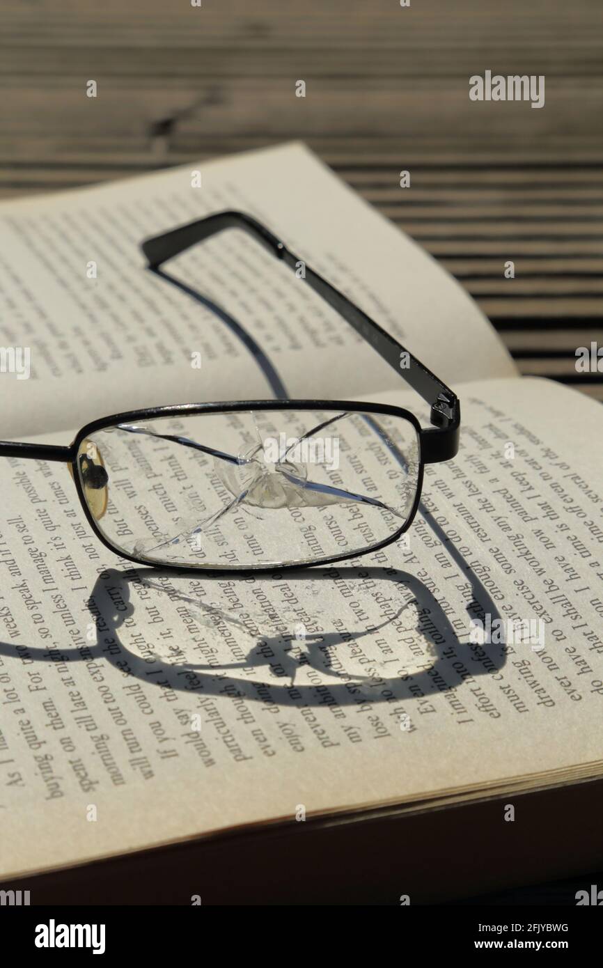 Broken reading glasses on the book Stock Photo