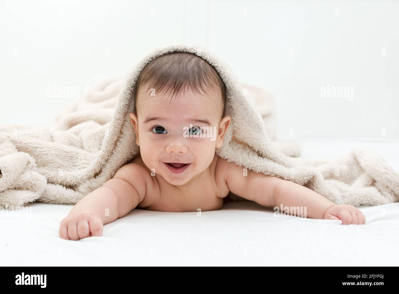Cute baby boy in bed under a fluffy blanket Stock Photo Alamy