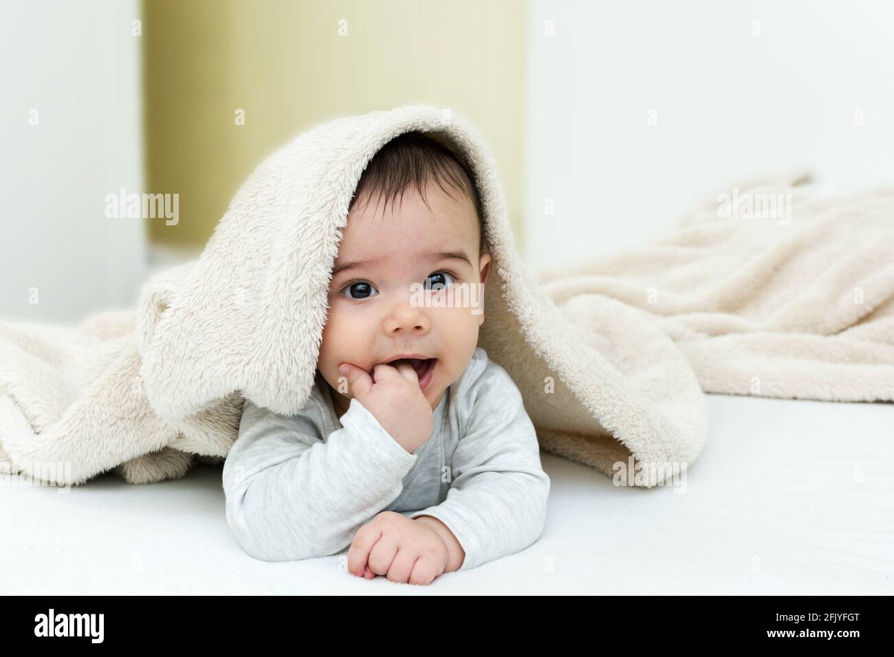 Cute baby boy in bed under a fluffy blanket Stock Photo Alamy
