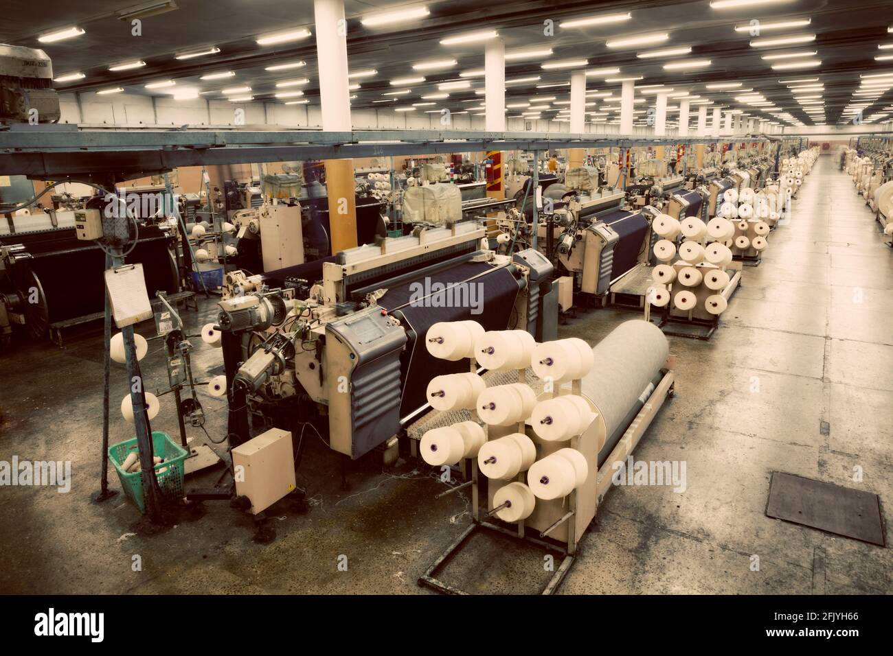 Weaving fabric on air jet looms in big textile weaving unit Stock Photo