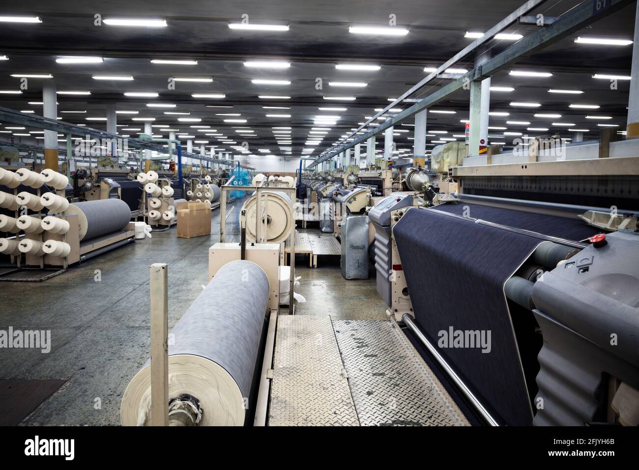 Weaving fabric on air jet looms in big textile weaving unit Stock Photo