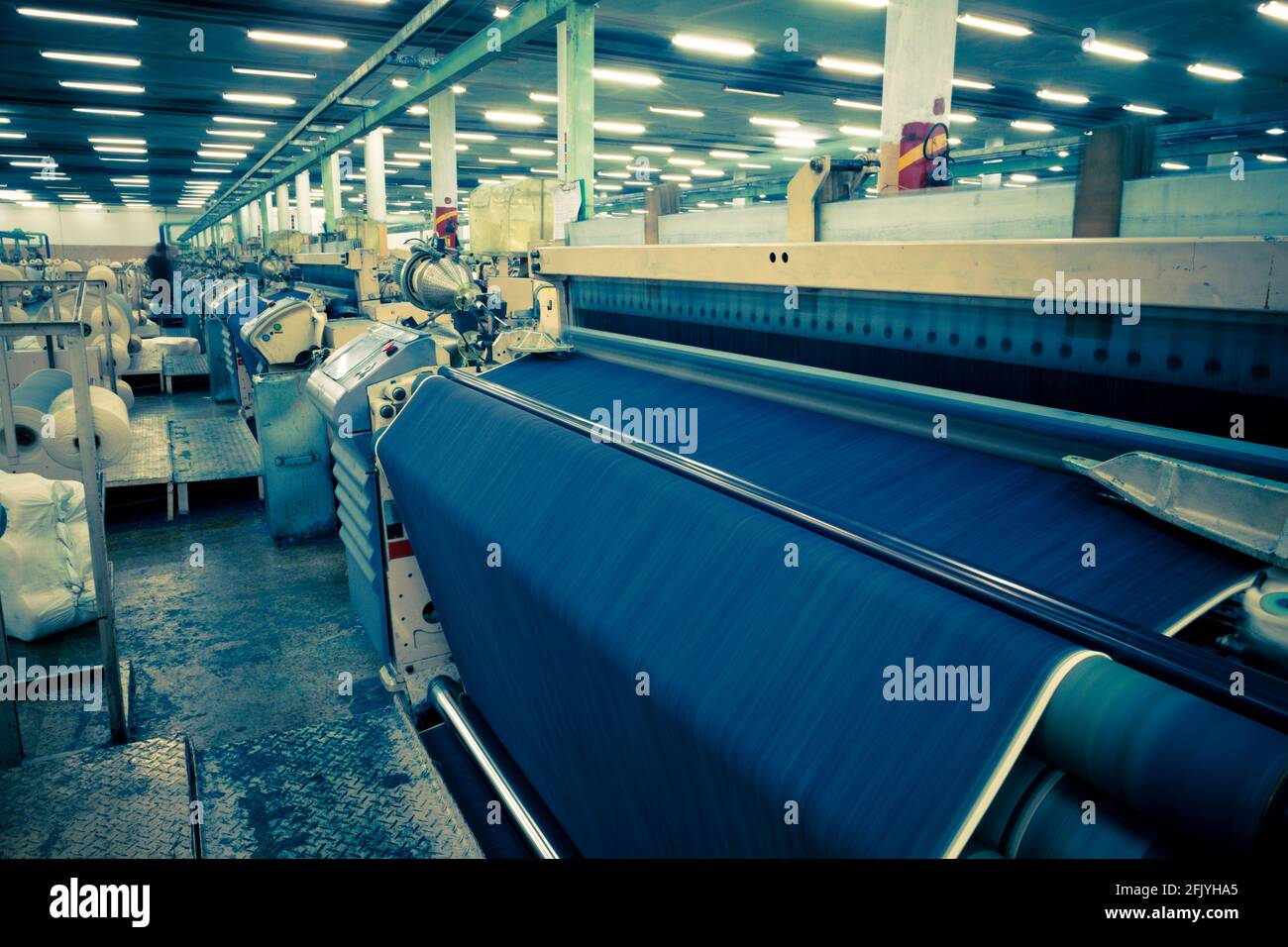 Weaving fabric on air jet looms in big textile weaving unit Stock Photo