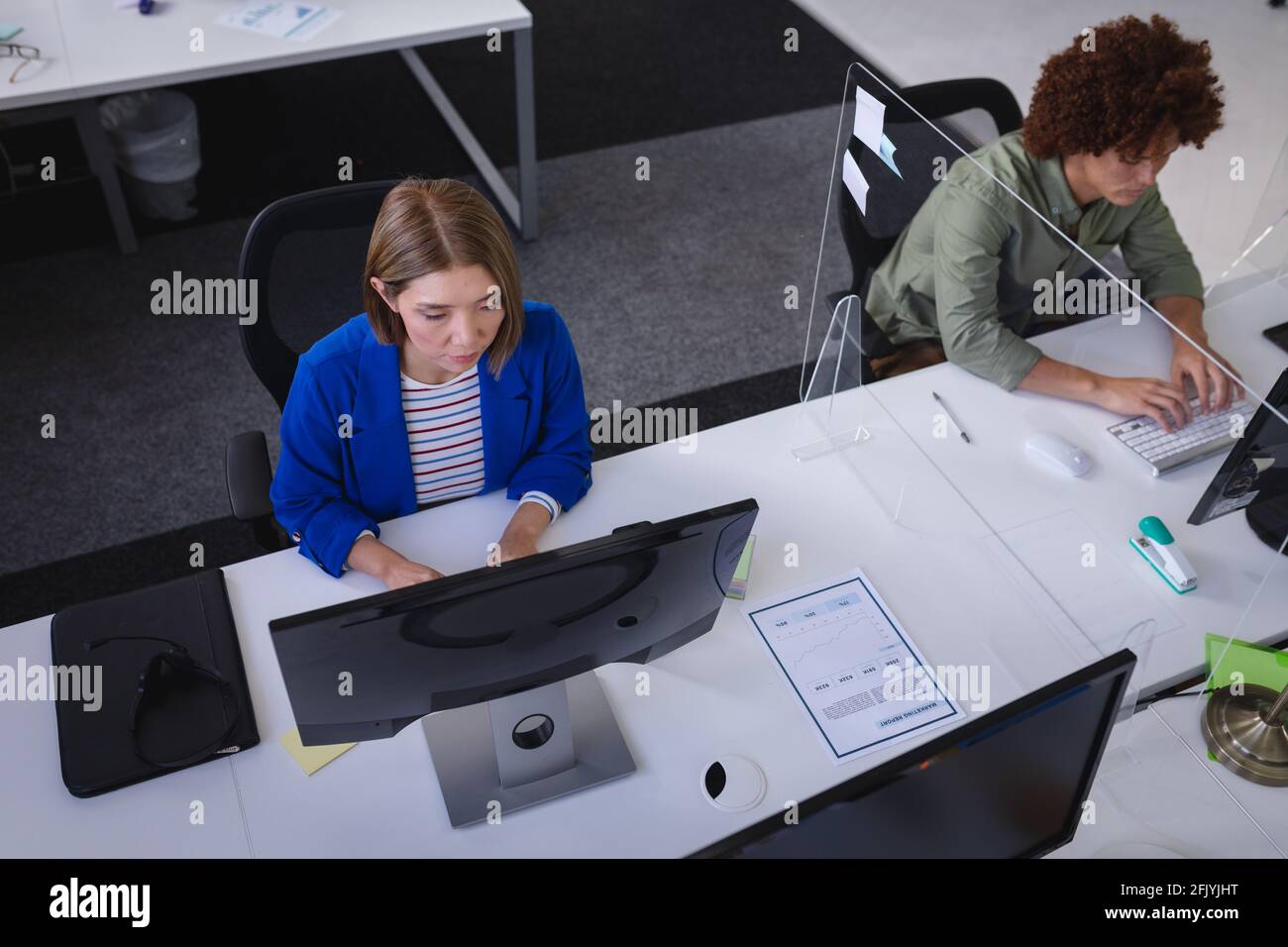 Diverse male and female colleagues sitting in front of computers ...
