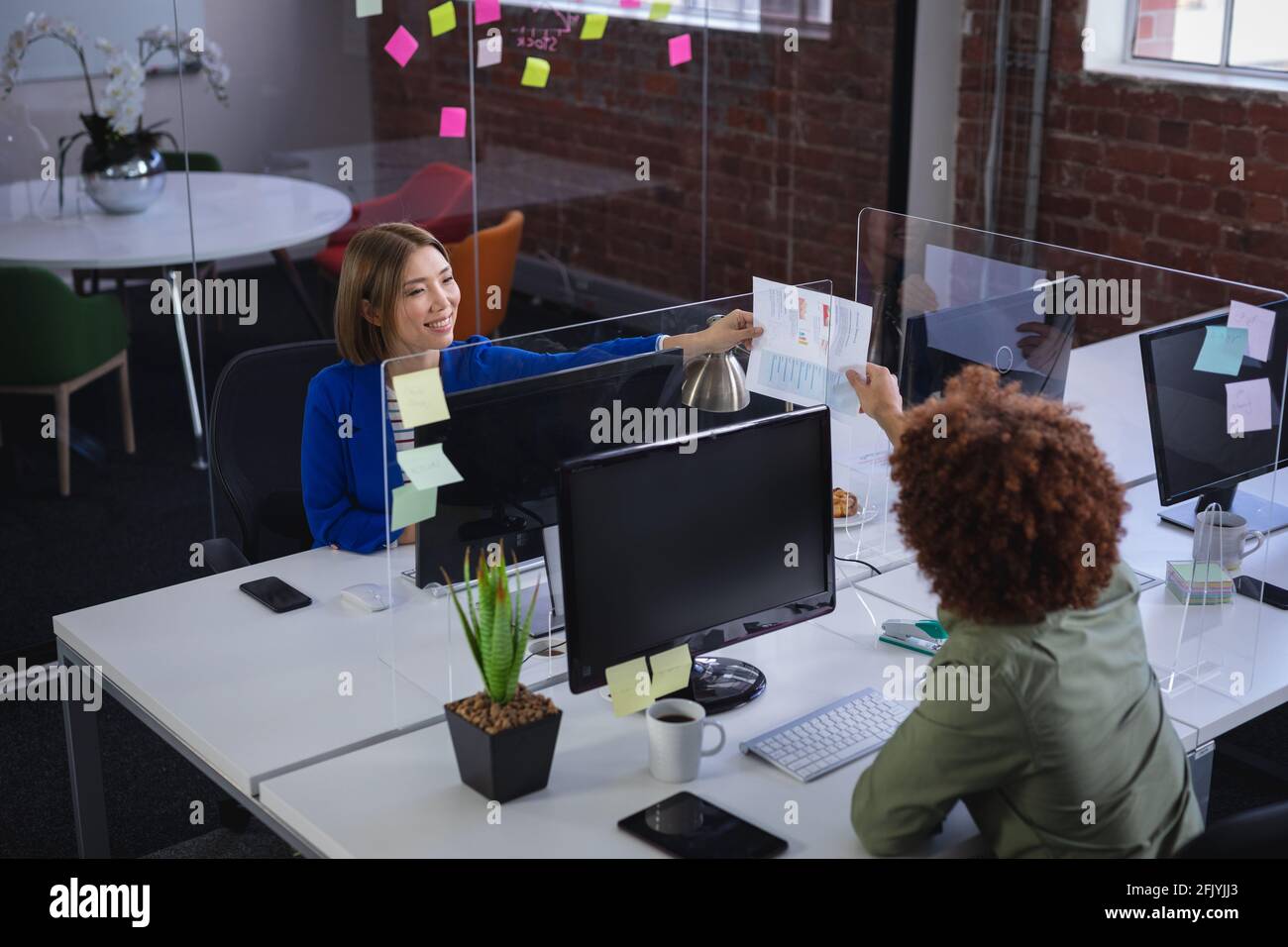 Diverse male and female colleagues in front of computers separated by ...
