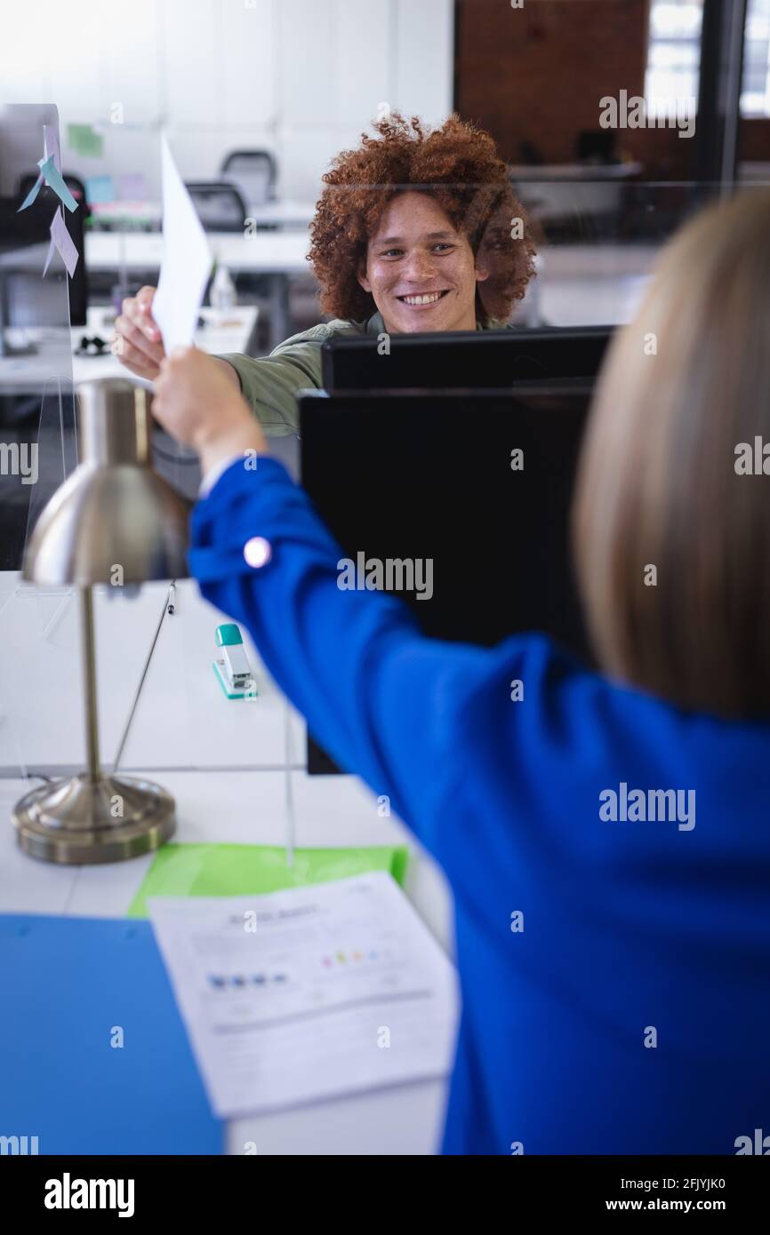 Diverse male and female colleagues in front of computers with sneeze ...
