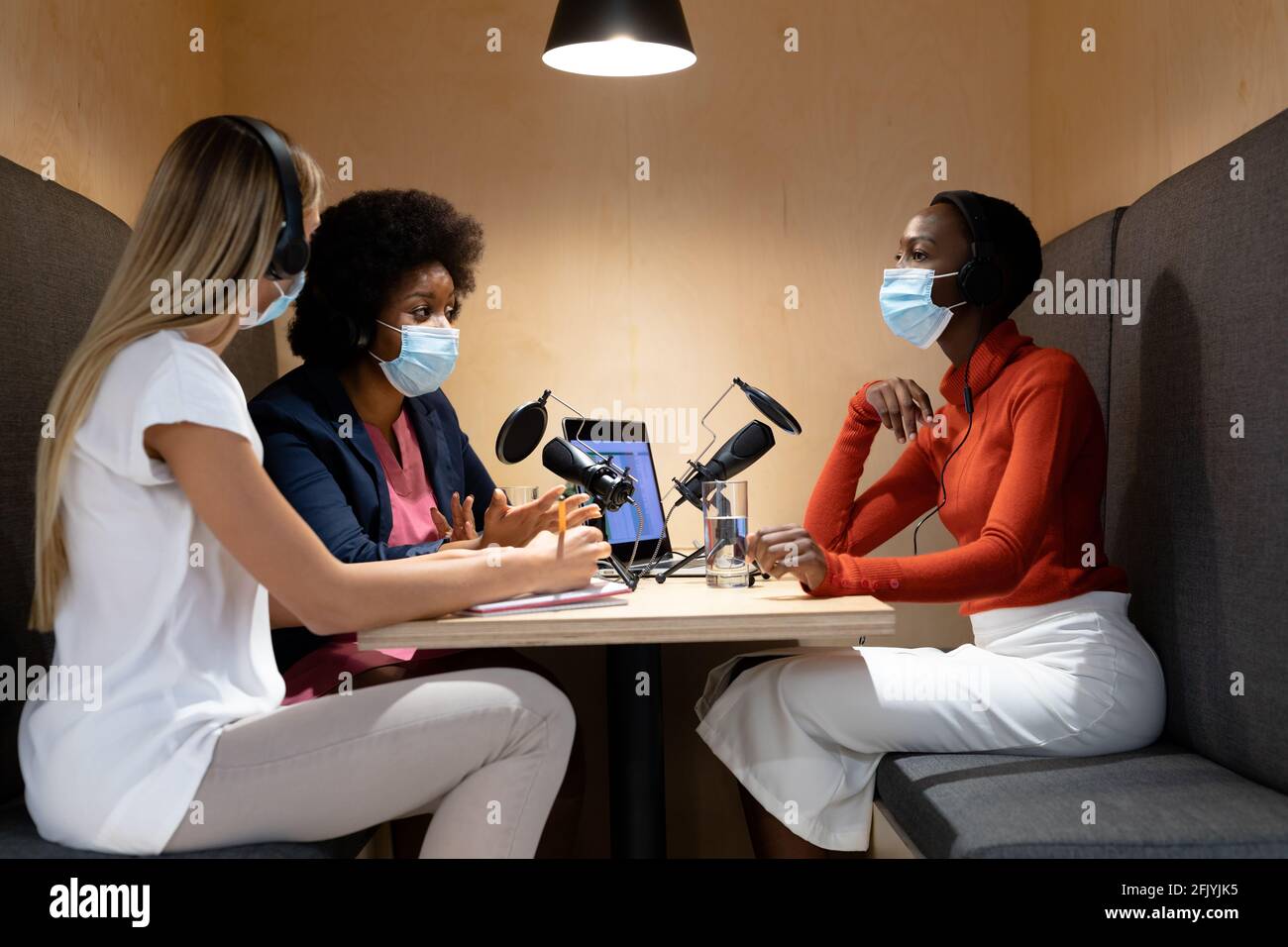 Diverse group of female business colleagues wearing masks in discussion ...