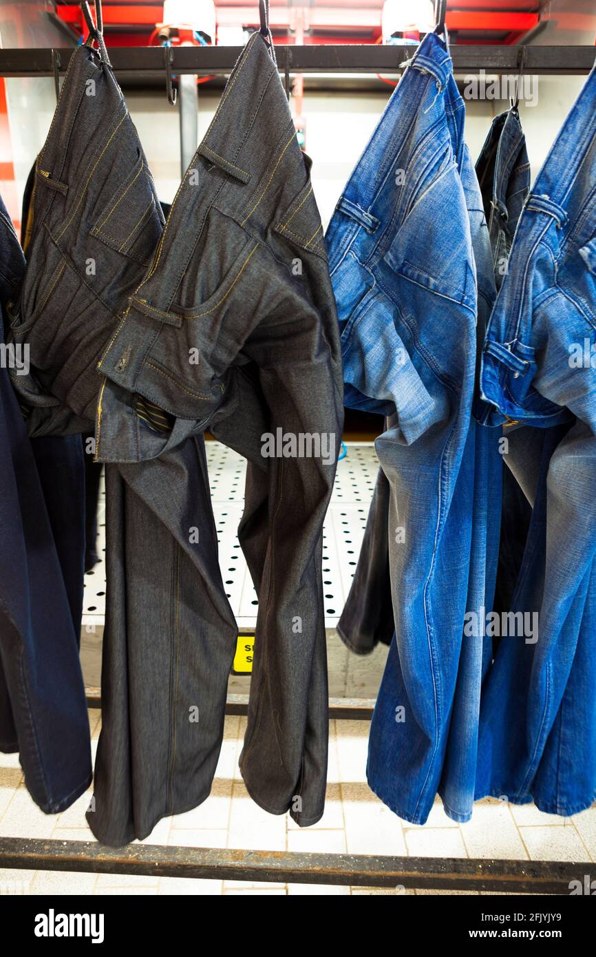 Jeans pants getting spray paints for special effects in denim manufacturing factory. Stock Photo