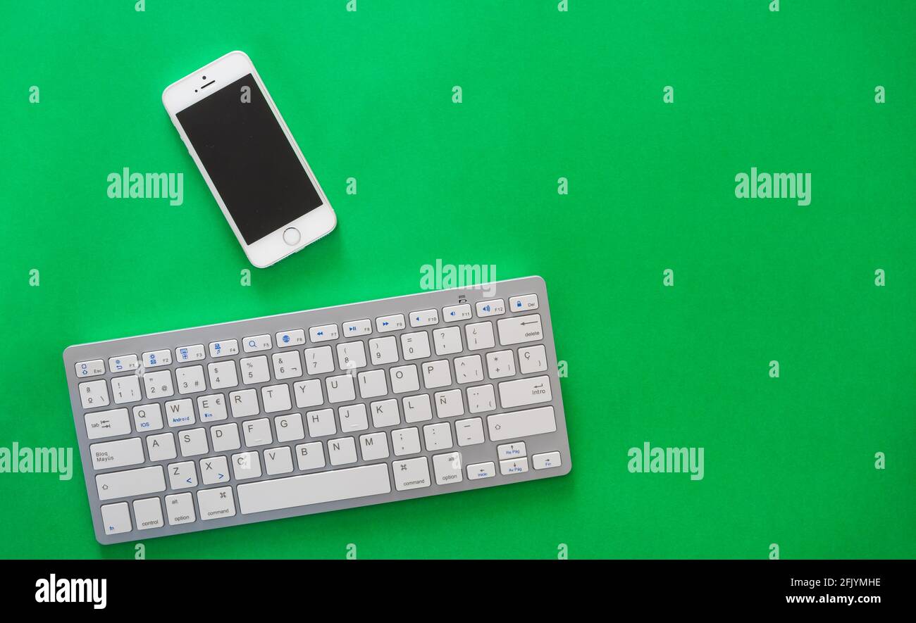 small wireless keyboard and mobile phone, on green background Stock Photo