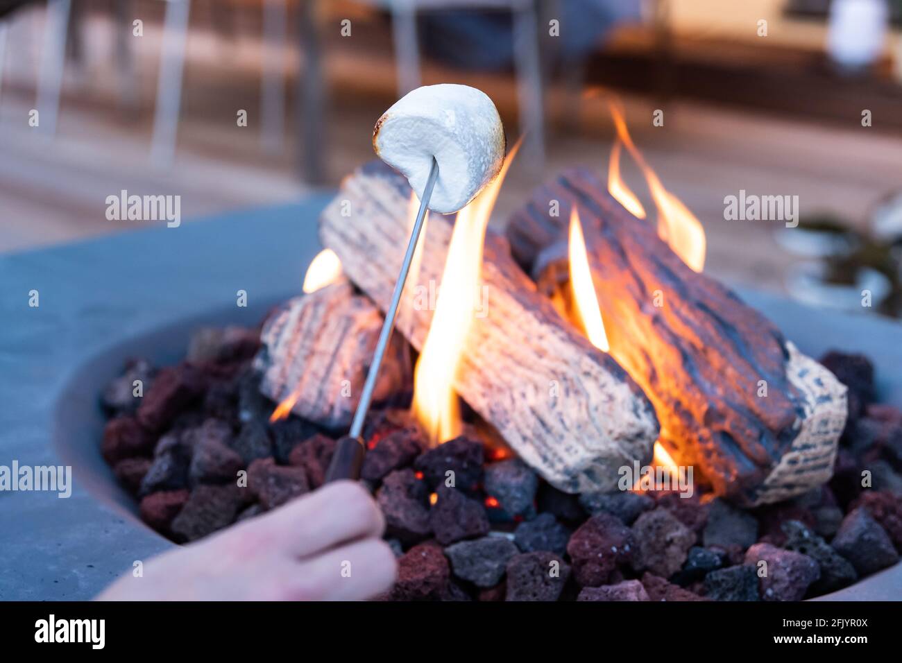 Roasting marshmallow over a gas fire while glamping Stock Photo Alamy
