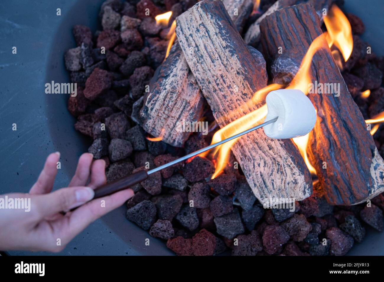 Roasting marshmallow over a gas fire while glamping Stock Photo Alamy