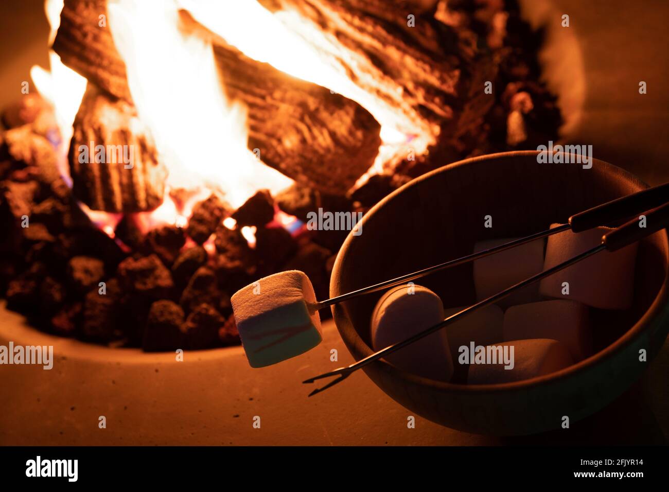 Roasting marshmallow over a gas fire while glamping Stock Photo Alamy