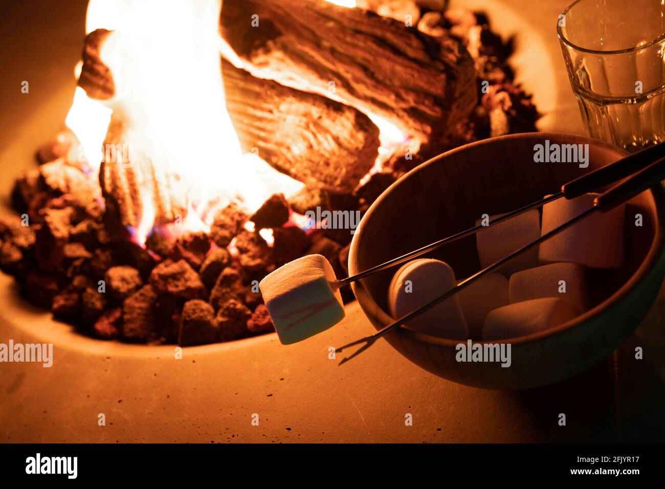 Roasting marshmallow over a gas fire while glamping Stock Photo Alamy
