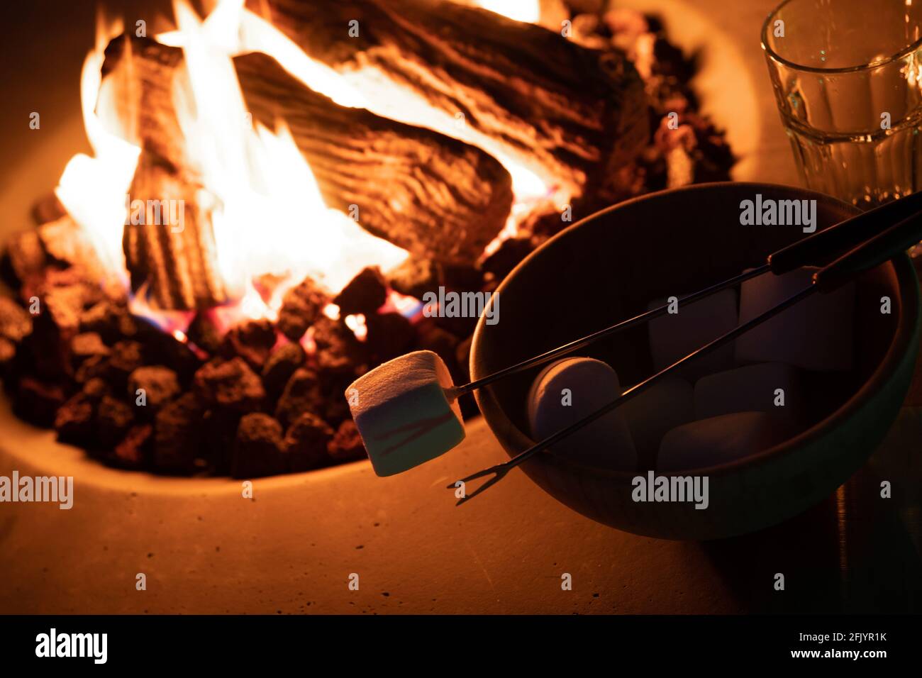 Roasting marshmallow over a gas fire while glamping Stock Photo