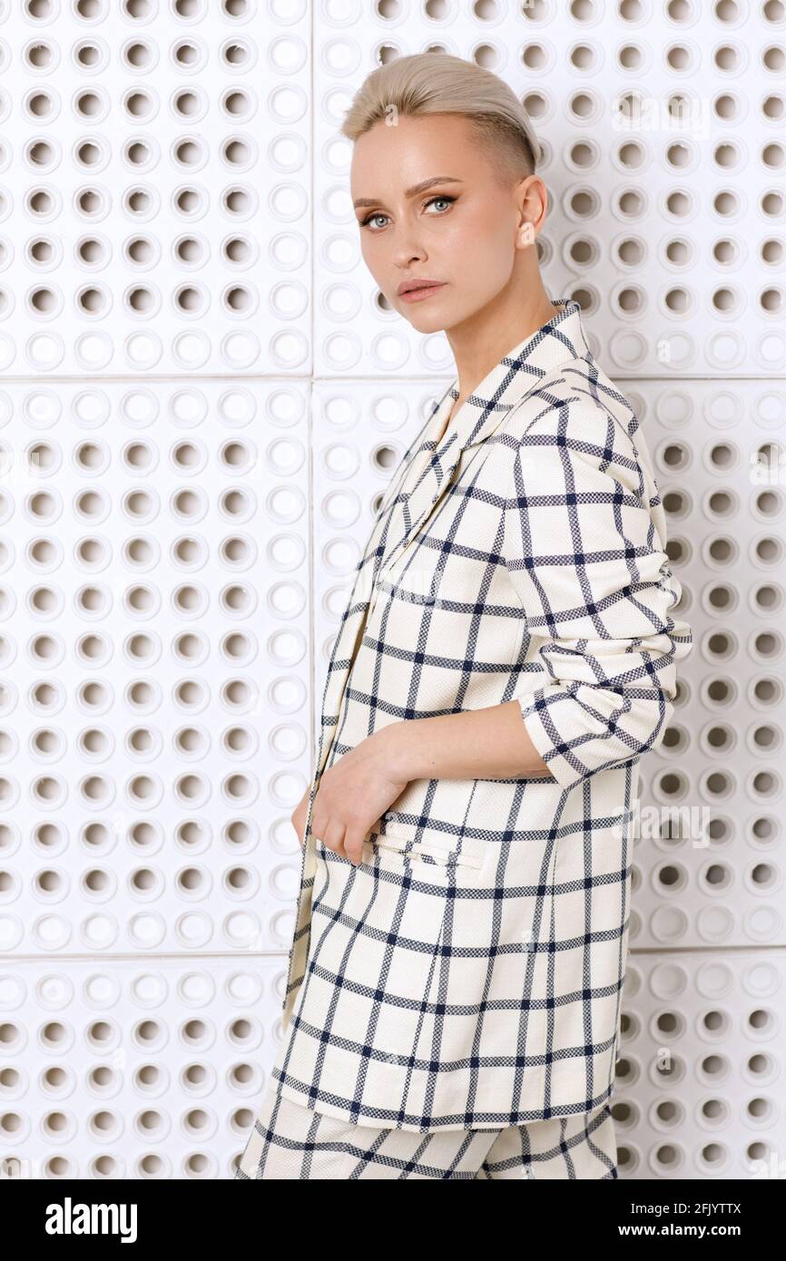Elegant ant charismatic short blond haired and natural makeup businesswomen wearing oversized linen suit with blue stripes posing isolated in studio Stock Photo