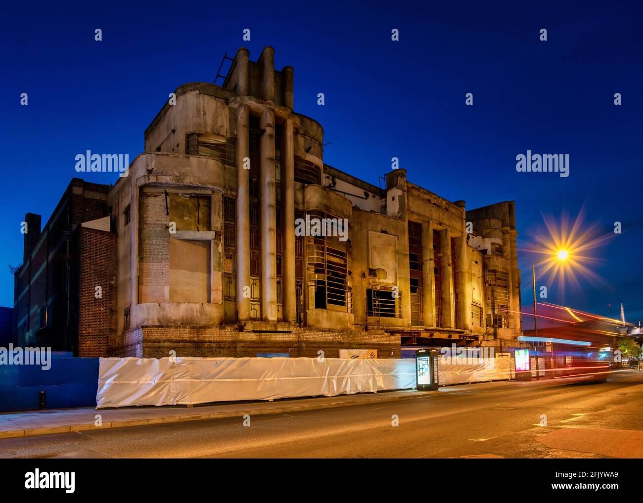 Harrow street by night with Art Deco Safari cinema building before renovation and London's red bus in motion, Harrow, England, Stock Photo