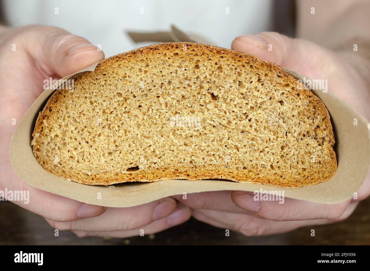 Close-up of a cross-section of bread in a man's hands. Man holds out to  camera a cut loaf of rye bread wrapped in paper Stock Photo - Alamy