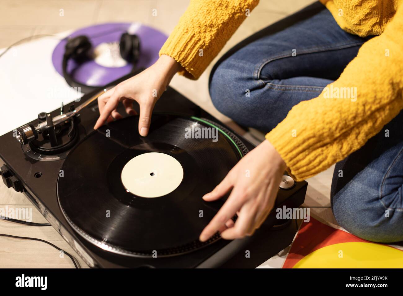 girl hands puts record on turntable. lounging at home with vinyl record