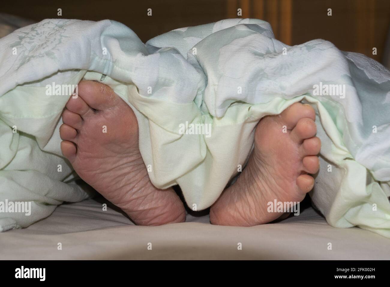 Sleep! Feet sticking out of bed Stock Photo