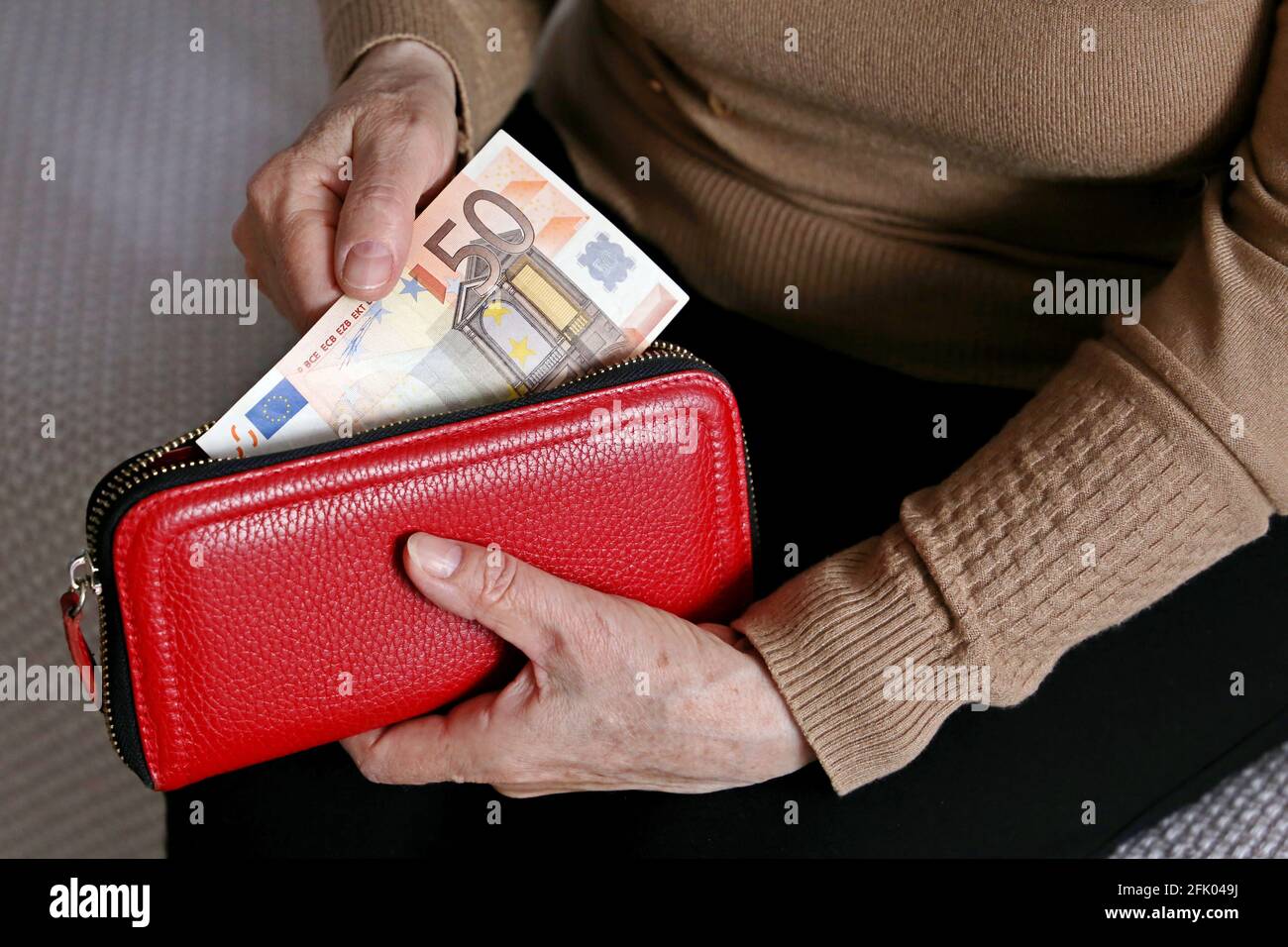 Elderly woman takes out a euro note from her wallet. Concept of pension payments, savings at retirement, pensioner with money Stock Photo